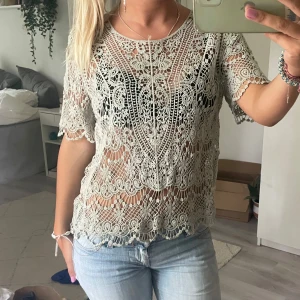 Ljusgrön spetsblus från Costes - Superfin ljusgrön blus från Costes med korta ärmar och detaljerat spetsmönster. Blusen är genombruten med vackra broderier och har rund halsringning. Perfekt att styla över ett linne eller bralette för en cool look.