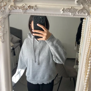 Grå hoodie med huva och snörning - Säljer en enkel och stilren grå hoodie med huva och snörning. Tröjan har en loose passform och är tillverkad i mjukt bomullsmaterial. 