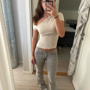 Snedskuren beige topp - Snedskuren beige topp från Ginatricot i storlek S. Den sitter tajt och har en ”scrunchad” sida. Säljer då den aldrig kommit till användning. 