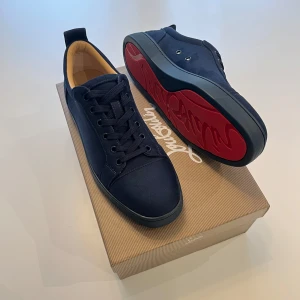 Mörkblå sneakers från Christian Louboutin - Snygga mörkblå sneakers från Christian Louboutin med ikonisk röd sula och signaturtryck undertill. Skorna har rund tå, platt sula och snörning. Utsidan är i mocka och insidan har beige foder. Perfekt för dig som vill sticka ut med exklusiv stil. Priset är inte satt i sten så hör av dig om du är intresserad!😁