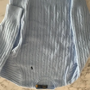 Ljusblå kabelstickad tröja Polo Ralph Lauren - Säljer en ljusblå kabelstickad tröja från Polo Ralph Lauren i storlek S. Tröjan har långärmade ribbade muddar och klassisk rund hals. Den är stickad i mjukt material och har den ikoniska lilla broderade loggan på framsidan. Perfekt för dig som gillar stilren och chill look. Sitter som en liten S stor xs. Använd 2 gånger 