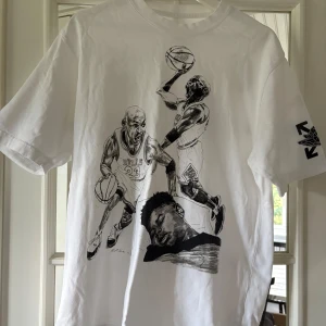 Off-White x Jordan vit t-shirt S - Vit t-shirt från Off-White och Jordan med stora svartvita basketillustrationer fram och bak. Tryck med Off-White-logga och pilar på ärmen. Skön passform och coolt motiv för dig som gillar streetwear och basket.