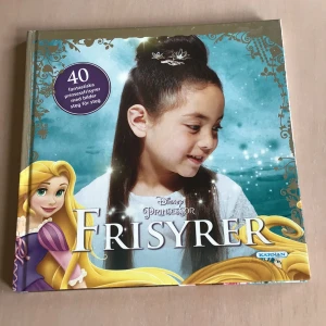 Disney Prinsessor Frisyrer - Lär dig skapa 40 magiska prinsessfrisyrer inspirerade av Disneyprinsessor! Boken visar steg för steg hur du fixar flätor, knutar och uppsättningar med bilder. Perfekt för dig som vill testa nya looks och leva ut dina prinsessdrömmar.
