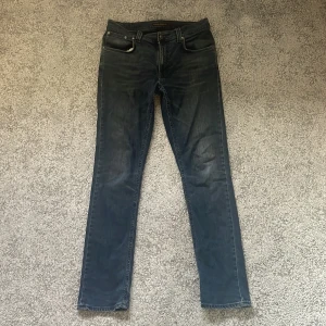 Mörkblå jeans från Nudie Jeans Co 32/32 - Säljer ett par mörkblå jeans från Nudie Jeans Co i storlek 32/32. Klassisk femficksmodell med snygga slitningar och Nudie-signaturen på bakfickan. Jeansen har en slim (thinn finn) passform och är tillverkade i mjukt denimtyg. Passar mig bra som är 182, kom dm vid frågor och funderingar.