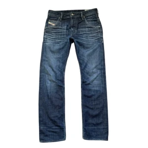 Mörkblå jeans från Diesel - Snygga mörkblå jeans från Diesel med klassisk femficksdesign och diskreta slitningar. Jeansen har en knappgylf och en läderpatch med logotyp på baksidan. Perfekta för en avslappnad stil. 