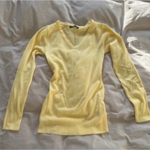 Ljusgul stickad v-ringad tröja Atmosphere - Supersöt ljusgul stickad tröja från Atmosphere i storlek S. Tröjan har v-ringad hals, långärmade ärmar och ribbad nederkant. Perfekt för dig som gillar mjuka och sköna material med enkel stil. Passar dig som vill ha en smalare passform. Den är en aning tight i passformen så den passar Xs också!