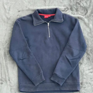 Marinblå half zip tröja från RYLS - Snygg marinblå tröja från RYLS med half zip och hög krage. Mjuk bomullskänsla och ribbade muddar vid ärmslut och nederkant. Perfekt för chill dagar eller när du vill ha en enkel men stilren look.