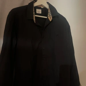 Svart Burberry skjorta XL  - Äkta Svart skjorta från Burberry i storlek XL med klassiska rutiga detaljer på insidan av kragen och armvecket, den passar dig som också har L pris kan alltid diskuteras 