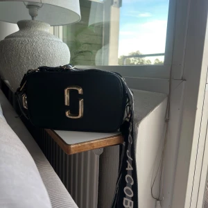 Svart axelväska Marc Jacobs - Snygg svart axelväska från Marc Jacobs med guldigt logospänne framtill. Använder inte alls längre vill ba bli av med den