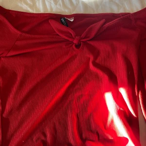 Röd ribbad tröja - Säljer en snygg röd ribbad tröja. en knytning framtill som ger en extra detalj. Perfekt för dig som vill sticka ut med en färgstark look.