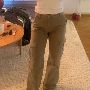 Gröna cargopants  - Säljer ett par snygga cargopants med breda ben och höga fickor på sidorna. Byxorna har hög midja och klassiska cargodetaljer som stora fickor på låren. 