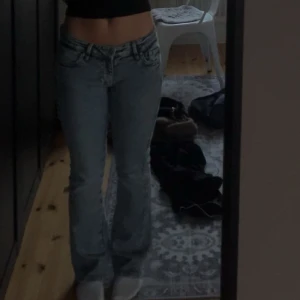 Bootcut ljusblå jeans från Gina tricot  - Säljer ett par ljusblå bootcut jeans från Gina tricot med snygga detaljer på bakfickorna. Jeansen har låg midja och är i ett otäjbart material. 