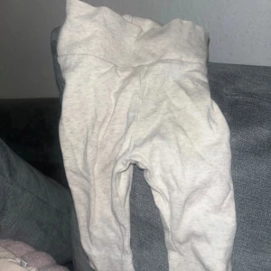 Ljusgrå mjukisbyxor med hög midja baby 1-3mån - Superbekväma ljusgrå mjukisbyxor med hög midja, perfekta för chill dagar hemma eller när du vill ha det extra skönt. Byxorna har en enkel design utan synliga detaljer och är gjorda i mjukt bomullsmaterial som känns skönt mot huden.