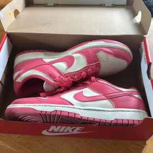 Nike Dunk i rosa och vitt - Snygga Nike Dunk sneakers i en fräsch kombination av rosa och vitt. Skorna har klassisk snörning och en bekväm passform.        De är endast testade. Köpta på zalando för 1500kr men säljer då dom var för stora.