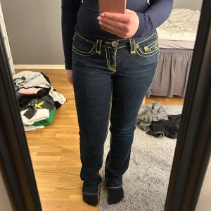 Mörkblå jeans från True Religion - Säljer ett par mörkblå jeans från True Religion med gul/brun stitching.