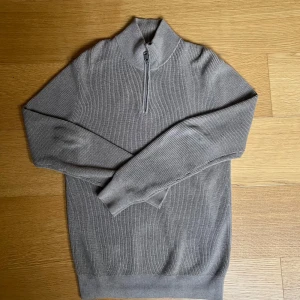 Grå ribbad tröja med dragkedja - Snygg grå ribbad tröja med dragkedja i halsen. Storlek S