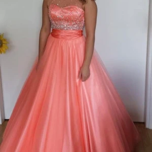 Korallfärgad balklänning  - Säljer min fantastisk  balklänning. Klänningen har en glittrig överdel med paljetter och en vacker snörning i ryggen. Som är ändrad för att passa en XS-S och INTE bara en XXS! 
