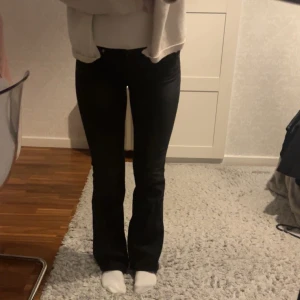 Lågmidjade svarta bootcut jeans - Snygga svarta bootcut jeans med knappdetaljer på bakfickorna. Använda 1 gång, Gina tricot Young stl 164