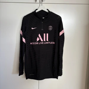 Svart långärmad fotbollströja från Nike x psg - Snygg svart långärmad fotbollströja från Nike med rosa detaljer och PSG-logga. 
