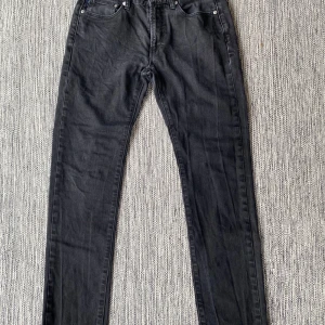Svarta jeans från Paul Smith w28 - Snygga svarta jeans från Paul Smith i en klassisk design. Tillverkade av 99% bomull och 1% polyuretan för en bekväm passform. De har en midwaist och raka ben, perfekt för en stilren look. Svarta jeans i strl w28 från Paul Smith.  Använda men i fint begagnat skick.  Tyvärr är lappen med storlek borta men vill minnas att det är en strl w28, dubbelkolla måtten enligt nedan.  Mått Midjan: ca 38 cm Längd från grenen och ner: ca 78 cm  99% bomull och 1% polyuretan   Kommer från ett djur / rökfritt hem