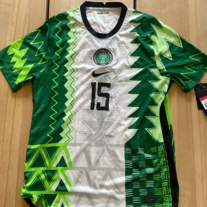 Nike Nigeria landslagströja nr 15 Dennis  - Säljer en grön och vit fotbollströja från Nike med ett unikt mönster och nummer 15 på både fram- och backsidan.  Tröjan är aldrig använd och är i nytt skick. Pris kan diskuteras vid snabb affär.