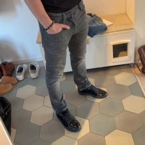 Jack and Jones  - Snygga grå jeansbyxor med en klassisk femficksdesign. De har en normal passform och är perfekta för en avslappnad stil. Byxorna har en dragkedja och knapp framtill.