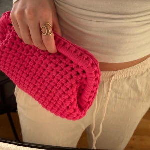 Rosa handvirkad väska/clutch - Säljer en mörk rosa handvirkad clutch / handväska som jag har virkat. Väskan är i ett mjukt garn och är väldigt rymlig! Kan bäras i handen som en clutch eller bäras i handtaget.  Kan Även Göra Andra Färger / storlekar💕