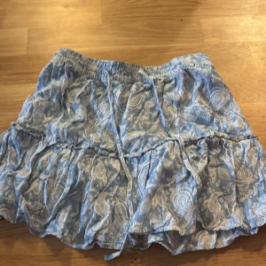 Zara kjol - Söt blå och vit kortkjol volanger. Kjolen har en elastisk midja och knytband för extra stil. Perfekt för en avslappnad sommarlook. Samt inbyggda shorts