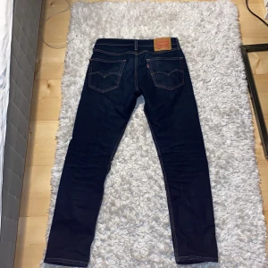 Mörkblå jeans från Levi's - Säljer ett par mörkblå Levi's 502 jeans. De har en klassisk femficksdesign och en knappgylf. Perfekta för en stilren look. Nypris 1200
