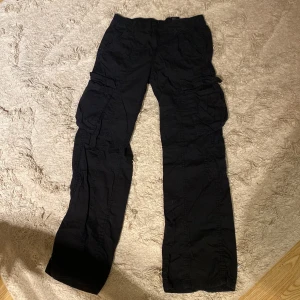 Svarta cargopants från Divided - Säljer ett par svarta cargopants från Divided. Byxorna har flera praktiska fickor och en elastisk midja för extra komfort. Perfekta för en avslappnad stil.