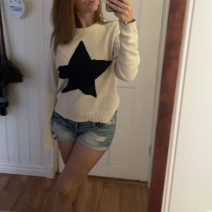 Vit stickad tröja med stjärna från Nelly - Säljer en vit stickad tröja från Nelly med en stor blå stjärna på framsidan. Tröjan har långa ärmar och en rund halsringning. Perfekt för en avslappnad stil. Knappt använd!💕