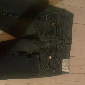Mörkblåa jeans från True Religion (skinny) - Snygga mörkblå jeans från True Religion med glittriga knappar och klassiska bakfickor. Bra skick! Mått: midjemått rakt över 35, grenhöjd 18, benöppning 13,5, lår 21,5 innerbenslängd 84 cm. Har inga bilder på då de inte passar 🩷🩷