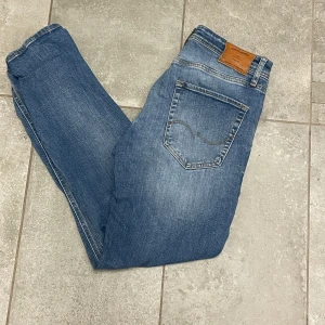Blå jeans från Jack n Jones - Snygga blå jeans från Jack n  med en klassisk femficksdesign. De har en lätt tvättad look med subtila slitningar och en normal passform. Perfekta för en avslappnad stil.