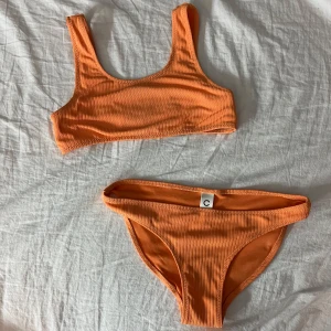 Orange ribbad bikini - Snygg orange bikini med ribbad struktur med breda axel band. Perfekt för en fin sommardag. Skriv vid frågor.
