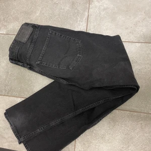 Svarta jeansbyxor Jack n Jones - Snygga svarta jeansbyxor med klassisk femficksdesign. De har en rak passform och är perfekta för en avslappnad stil. Byxorna har en knappgylf och är tillverkade i ett robust denimtyg.