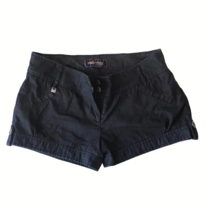 Svarta/mörk grå shorts från Philip Russel - Svarta shorts från Philip Russel i denim. De har en låg midja och knappar framtill. 