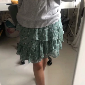 Minikjol - Säljer en superfin grön blommig minikjol från Stradivarius i storlek XS. Perfekt för sommaren eller våren! Den har en elastisk midja för extra komfort💚