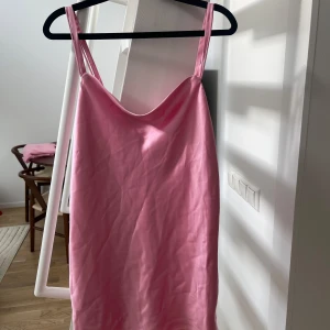 Rosa klänning från Zara - Säljer en söt rosa klänning från Zara med smala axelband. Perfekt för varma dagar och ger en fräsch look. Klänningen har en enkel och stilren design.
