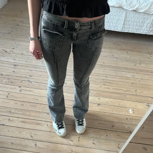 Grå jeans från Nelly - Bootcut lågmidjade. Väldigt bra skick men slitna längst ner.