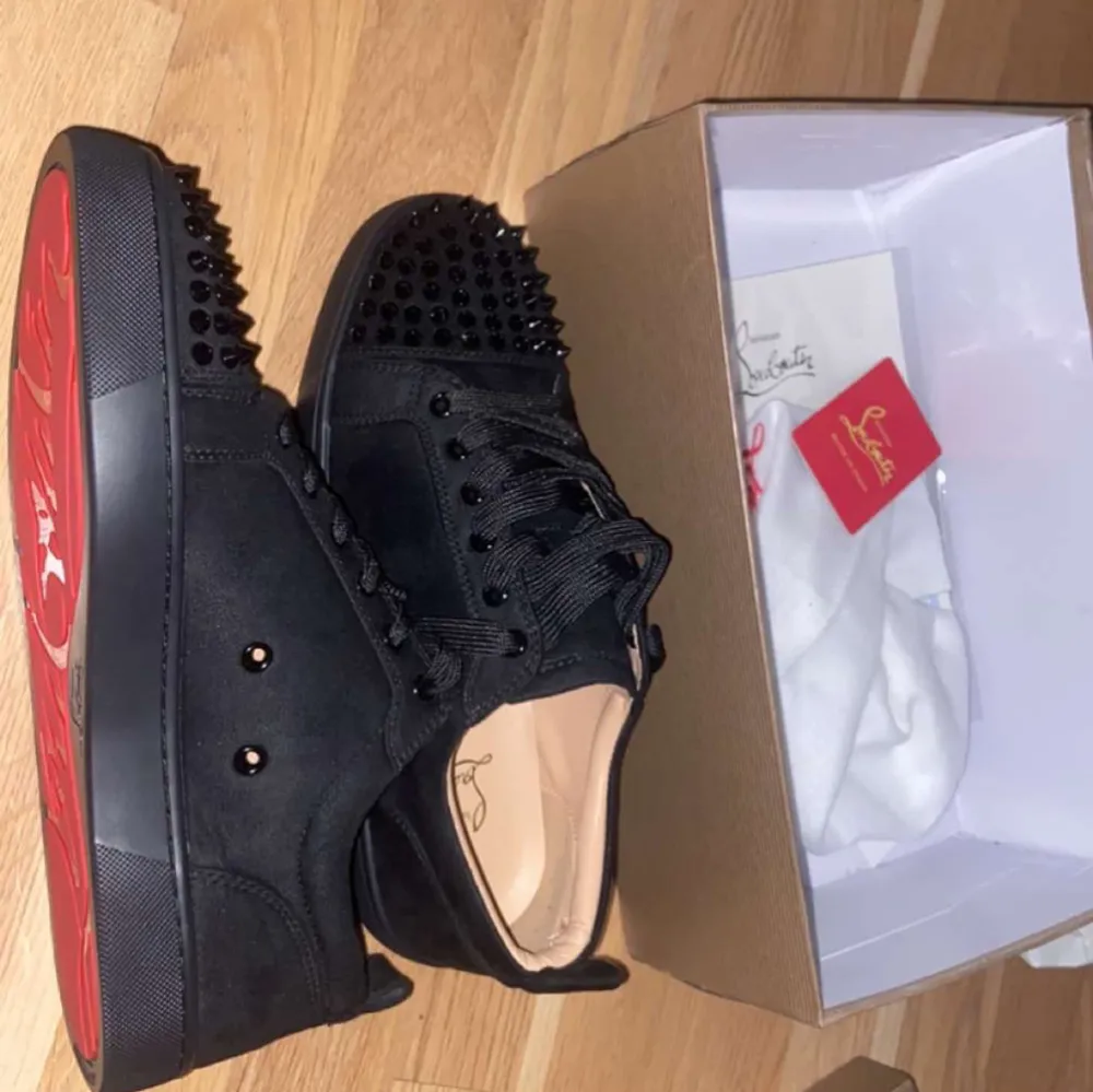Snygga svarta sneakers från Christian Louboutin med nitar på tån och sidorna. Skorna har den ikoniska röda sulan och snörning framtill. Perfekta för att ge din stil en edgy touch.. Kengät.