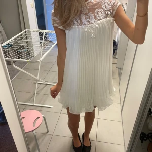 Vit klänning - Kort vit klänning med stenar och plisserad nertill. Supersöt och endast använd en gång. Små defekter finns vid stenarna men inget som man tänker på! 