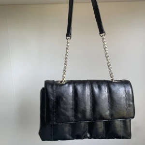 svart skinnväska  - Svart skinnväska från zara med kedja. Inga skador eller smuts! Använt sparsamt och jättefint skick🥰 Finns 3 större fack och ett mindre fall på baksidan av väskan och även ett litet fack inuti väskan🥰