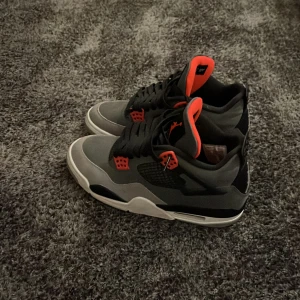 Grå och svarta sneakers - Snygga grå och svarta sneakers med röda detaljer. Skorna har en klassisk design med snörning och en bekväm sula. Perfekta för både vardag och sportiga aktiviteter. En konkurrens kraftig sko som är i väldigt bra skick för detta pris, de bästa priset du kan hitta på marknaden.