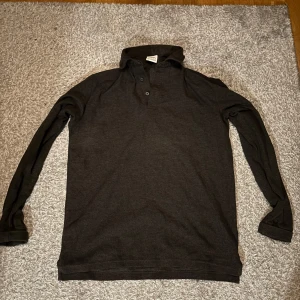 Brum pikétröja - Säljer en stilren brun pikétröja med långa ärmar och klassisk krage. Perfekt för en avslappnad men ändå uppklädd look. Tröjan har knappar framtill och är i en bekväm passform. Från Zara