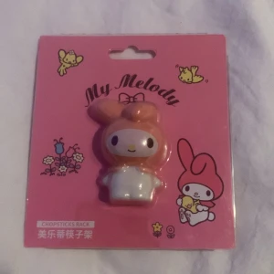 My Melody Chopsticks Rack från Sanrio - Söt My Melody chopsticks rack från Sanrio. Perfekt för att hålla dina ätpinnar på plats. Kommer i en rosa förpackning med gulliga illustrationer av My Melody och blommor.