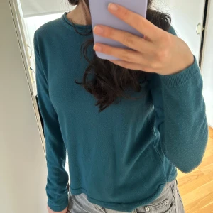 Petrolblå tröja från Softie - Säljer en stilren petrolblå tröja från Softie. Tröjan har en rund halsringning och långa ärmar, perfekt för en avslappnad look. Den är tillverkad i ett mjukt material som känns skönt mot huden. Passar bra till både jeans och kjol. 