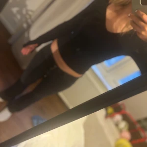 Svart långärmad topp - Snygg svart långärmad topp som är v-ringad och slits vid armarna. Toppen har en tight passform som sitter skönt mot kroppen. Perfekt för en stilren look!