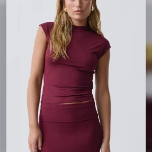 Vinröd ärmlös topp - Snygg vinröd ärmlös topp med hög hals. Perfekt för en stilren look. Tillverkad i ett mjukt och stretchigt material som ger en bekväm passform. Nästan helt oanvänd. 