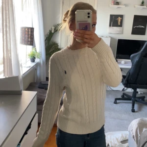 Vit stickad tröja från Ralph Lauren - Säljer min vita stickad tröja från Ralph Lauren med klassiskt flätmönster. Tröjan har långa ärmar och en rund halsringning. Perfekt för både kyligare dagar och en sommar kväll 😊den har en kommit till användning på ett tag derför jag säljer den, den har st S men känns mer som en M 💕