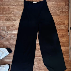 Svarta vida byxor - Snygga svarta byxor med en vid passform och hög midja. Byxorna har en enkel design utan mönster eller detaljer, vilket gör dem lätta att matcha med olika toppar. Har en liten dragkedja på sidan. Lite kostymbyxiga i modellen😍 